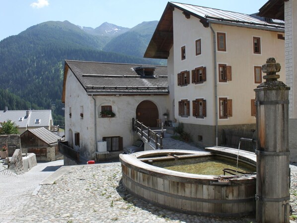 A traditional building with a courtyard, stone flooring, and a wooden water feature.