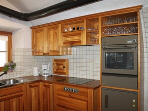 A kitchen with wooden cabinets, a built-in oven, and a coffee maker. - Chasa Crusch 117, (Ardez) by Interhome (Ardez)