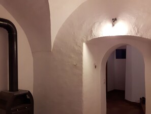 A hallway with a black vacuum cleaner and a light fixture on the wall.
