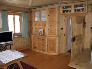 A wooden interior with a television, a table with a lace tablecloth, and a cabinet with drawers. - Chasa Crusch 117, (Ardez) by Interhome (Ardez)