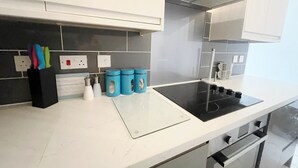 Eine moderne Küche mit weißen Schränken, einer schwarzen Induktionskochplatte und einer Edelstahl-Dunstabzugshaube.