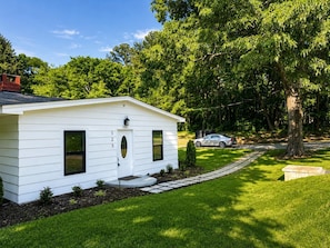 A white single-story house with a front door, two windows, and a small porch.