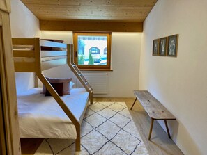 A compact room with a bunk bed, a window with a view of a car and trees, a small bench, and a radiator. - Ferienwohnungen Chà d’Immez, (Müstair) by Interhome (Müstair)