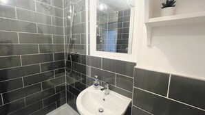 Un bagno con piastrelle nere, un lavandino bianco e uno specchio.