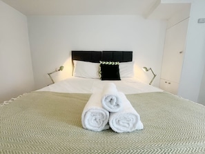 A neatly made bed with white linens, a black headboard, and two bedside lamps. - Anstey Heights - Apartment 6 - Hopewell (Easton)