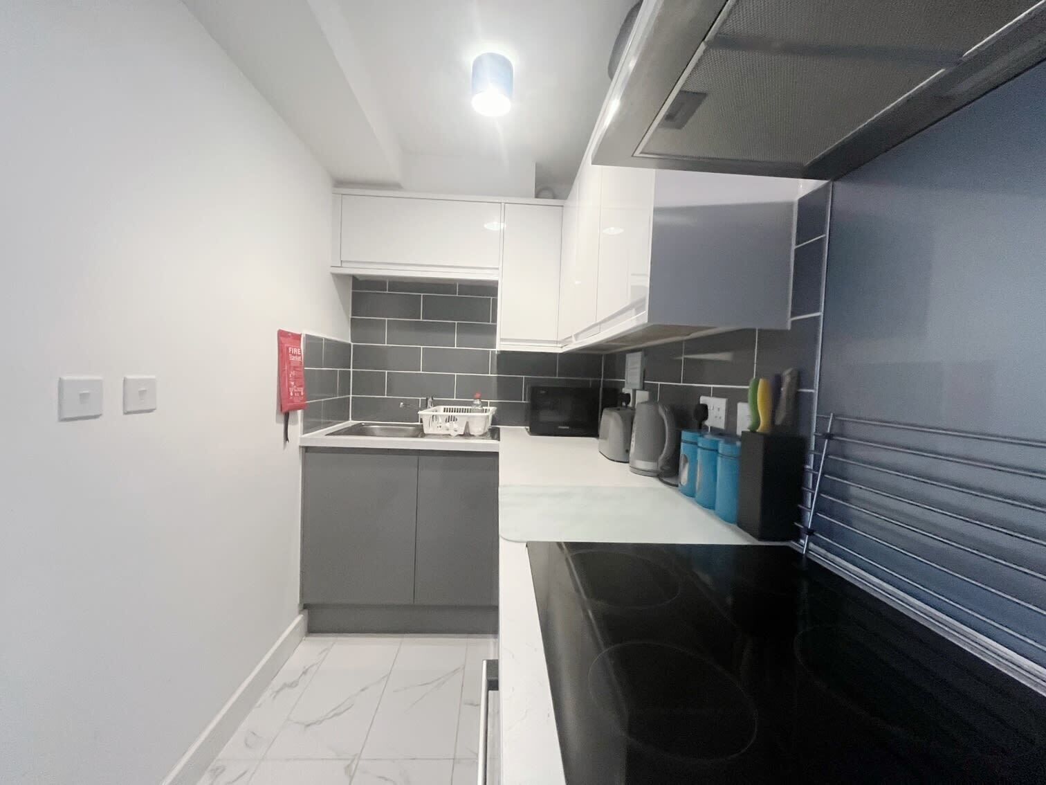A modern kitchen with grey cabinets, a black countertop, and a microwave.