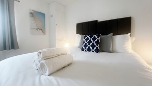 A neatly made bed with white linens, a headboard, and decorative pillows. - Anstey Heights - Apartment 3 - Hopewell (Easton)