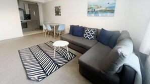A modern living room with a grey sofa, a small white table, and a striped rug. - Anstey Heights - Apartment 3 - Hopewell (Easton)