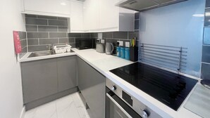 A modern kitchen with white cabinets, a black stove, and a tiled backsplash. - Anstey Heights - Apartment 3 - Hopewell (Easton)