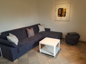 A living room with a dark blue sectional sofa, a white coffee table, and a small ottoman. - Iten, (Ftan) by Interhome (Ftan)