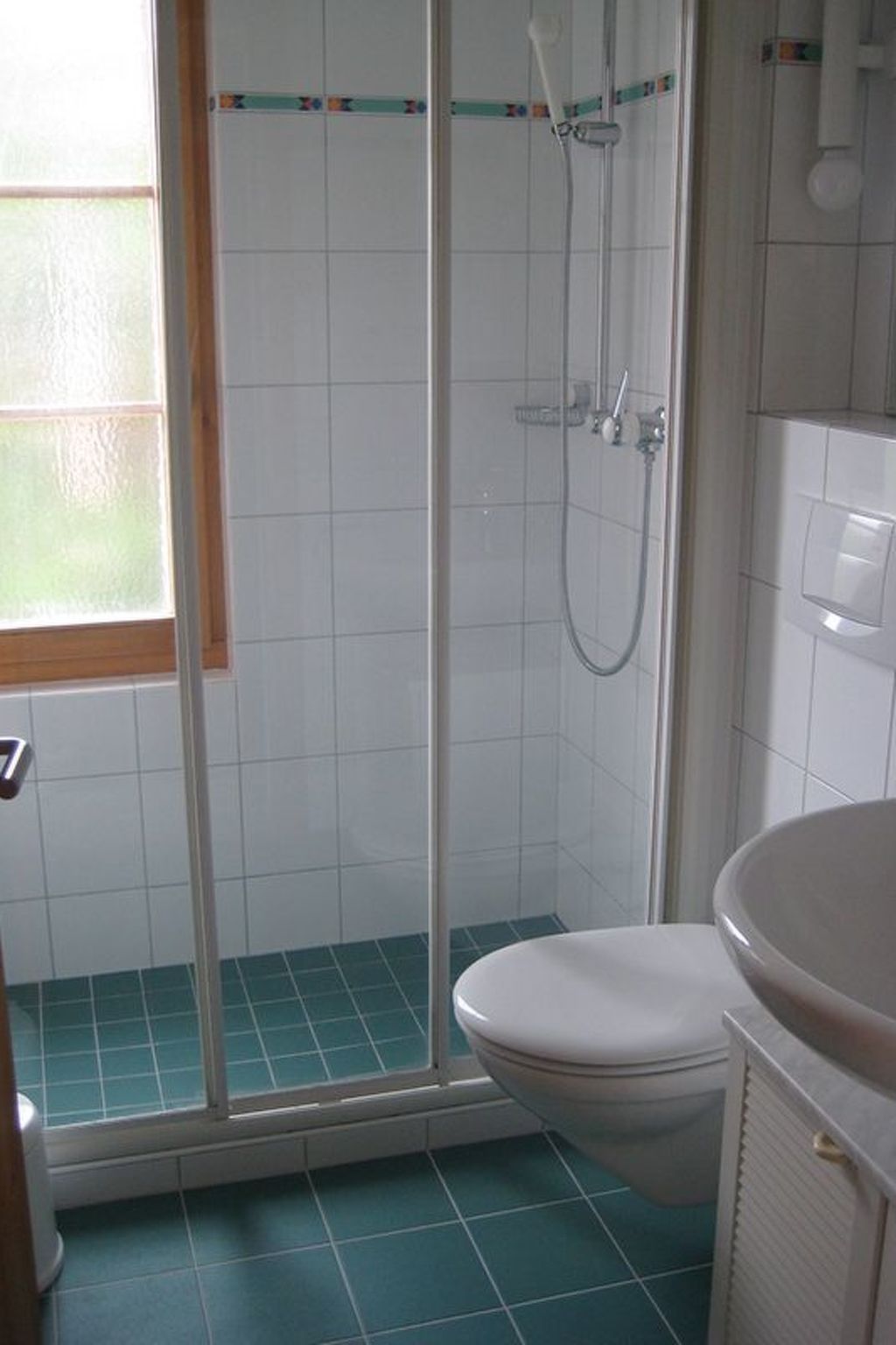 A bathroom with a shower enclosure, a toilet, and a sink.