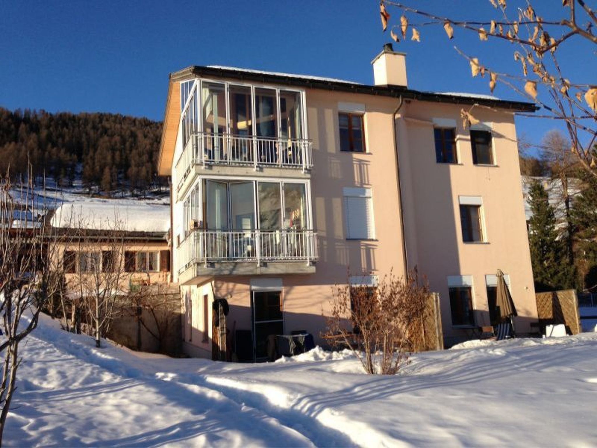 Edificio de dos pisos con un balcón en el nivel superior, rodeado de nieve.