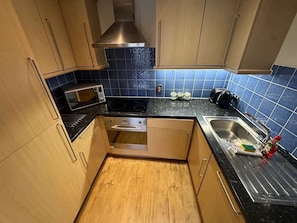 Eine kleine Küche mit Holzausstattung, einer Mikrowelle, einem Toaster und einem Spülbecken.