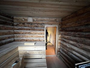 Interior d'una cabana de fusta amb una escala de fusta que condueix a una porta.