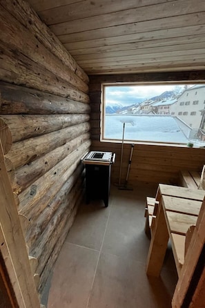 Una cabana de fusta amb interior de fusta, una finestra amb vista a un paisatge nevàt i una taula petita amb un teclat.