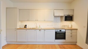 Une cuisine moderne avec des armoires blanches, un four encastré et un four à micro-ondes.