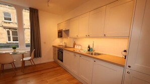 Een moderne keuken met witte kasten, een houten aanrecht en een raam met gordijnen.