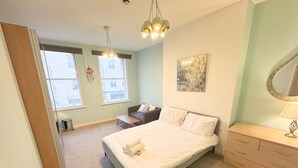 Een slaapkamer met een bed, een dressoir, een stoel en een raam.