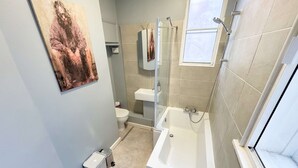 Een badkamer met een bad, toilet en een douchecabine.