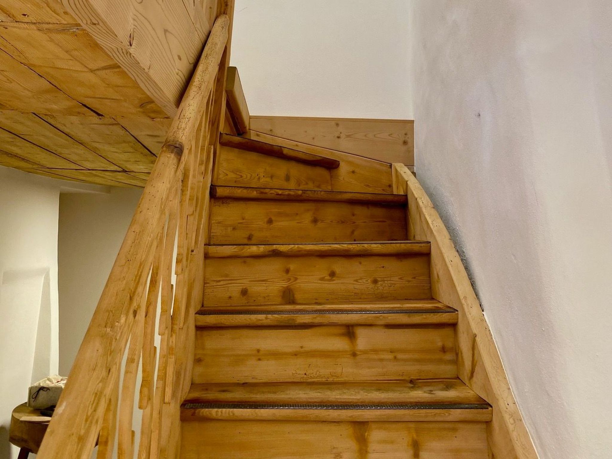 Una escalera de madera con barandilla que lleva a un piso superior.