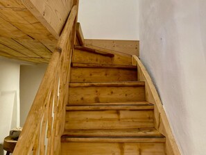 A wooden staircase with a handrail, leading to an upper floor. - Ferienwohnungen Chà d’Immez, (Müstair) by Interhome (Müstair)