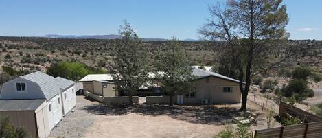 A single-story house with a garage, a fenced yard, and a view of a desert landscape with mountains in the distance.