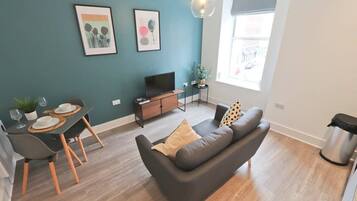 A modern living room with a sofa, dining table, and TV.