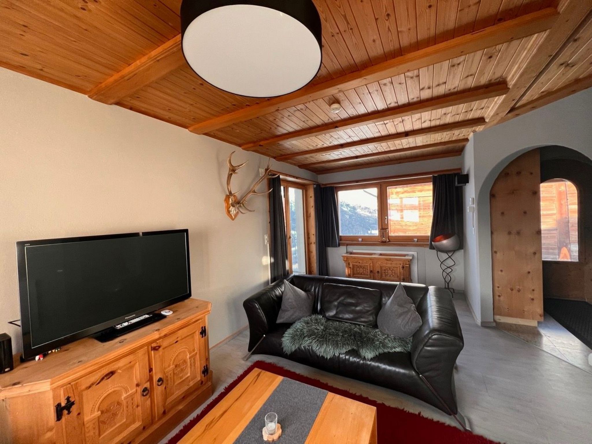 A living room with a television, leather sofa, wooden cabinet, and a fireplace.