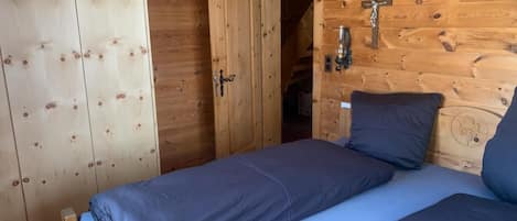 Una habitación de madera con una cama, un armario y una puerta que da a otra habitación.