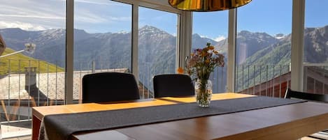 A dining area with a table, chairs, and a vase with flowers.