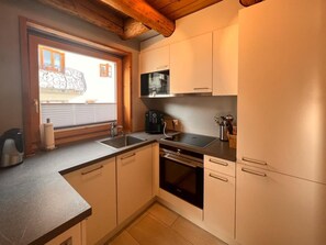 A compact kitchen with a sink, stove, and microwave. - Bergblick-Craistas, (Sta. Maria - Santa Maria Val Müstair) by Interhome (Sta. Maria GR)