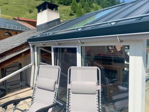 A conservatory with two chairs and a glass door, overlooking a green landscape. - Bergblick-Craistas, (Sta. Maria - Santa Maria Val Müstair) by Interhome (Sta. Maria GR)