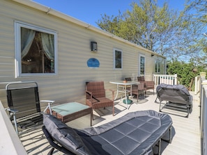 A mobile home with a patio area featuring a table, chairs, a lounge chair, and a grill. - Valley Farm Number 448 (Clacton-on-Sea)