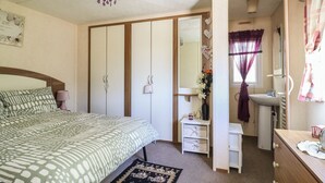 Een slaapkamer met een bed, een kast, een dressoir, een kaptafel en een spiegel.