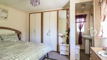 Une chambre à coucher comprenant un lit, une armoire, une commode, une coiffeuse et un miroir.