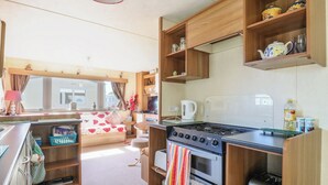 Een compact keukenblok in een camper, met een kookplaat, oven en een klein spoelbakje.