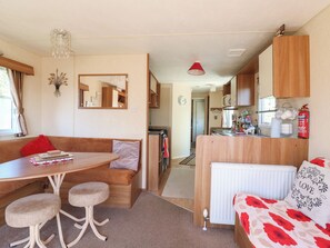 A compact RV interior with a dining area, kitchenette, and a cozy seating space. - Valley Farm Number 448 (Clacton-on-Sea)