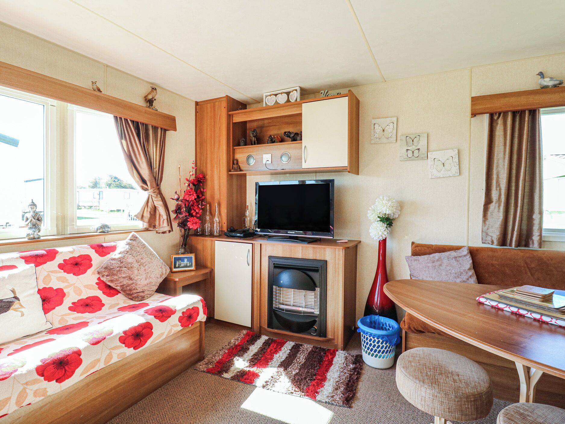 A cozy RV interior with a sofa, a dining table, a TV, and a small kitchen area.