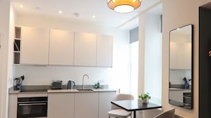 Eine moderne Küche mit weißen Schränken, einer Spüle, einem Herd und einem Essbereich mit Tisch und Stühlen.