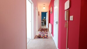 A hallway with a colorful rug, a radiator, and a light switch on the wall. - Stylish 2 Bed in Old Market (Bristol)