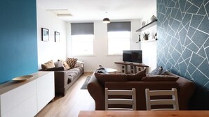 A modern living room with a sofa, a dining table, and a TV. - Stylish 2 Bed in Old Market (Bristol)