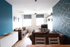 Ein modernes Wohnzimmer mit einer Couch, einem Esstisch und einem Fernseher.