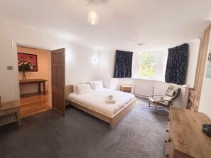 A bedroom with a bed, a chair, a wooden dresser, a window with curtains, and a door leading to another room. - On Bedroom Redland retreat Parking (Bristol)