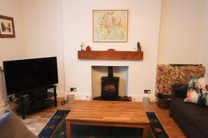 A living room with a TV, fireplace, and sofa. - Fernbank One Bed with Garden (Bristol)
