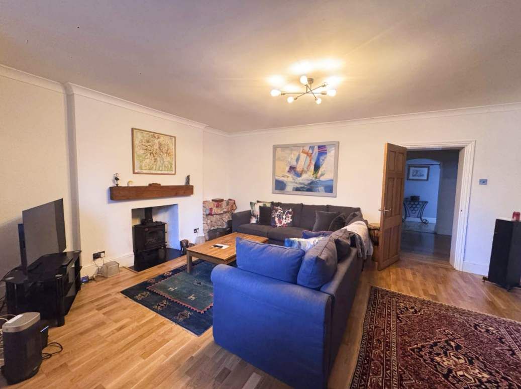 Een woonkamer met een bank, salontafel, televisie en open haard.
