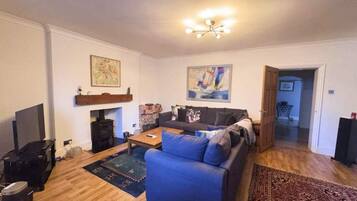 Een woonkamer met een bank, salontafel, televisie en open haard.