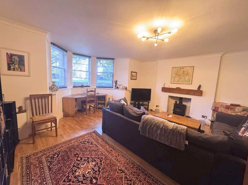 A living room with a sofa, a television, a fireplace, and a dining area.