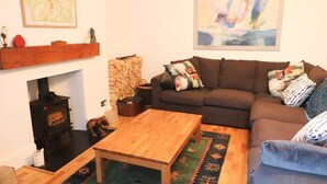 Een woonkamer met een bank, een houten salontafel, een open haard en een stenen muur.