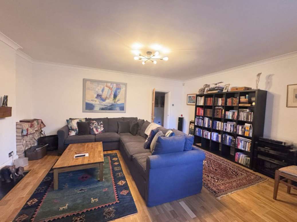 Een woonkamer met een bank, salontafel en een boekenkast.