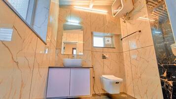 A bathroom with a marble wall, a white sink, a mirror, and a toilet.